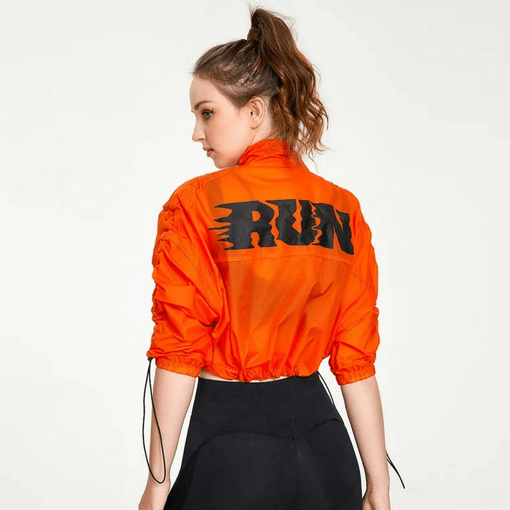 Woman in neon orange athletic jacket with 'RUN' text, showcasing sporty style and breathability, ideal for outdoor activities.